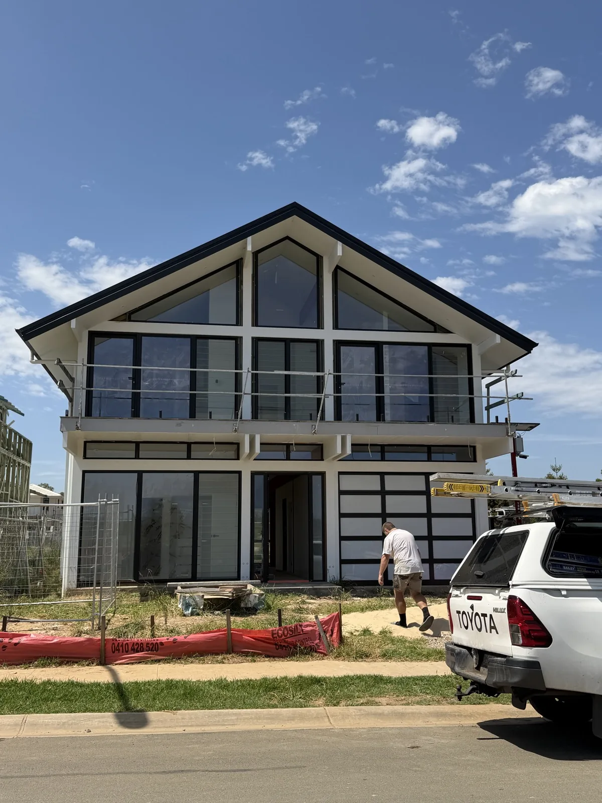 Two-storey new build with raked gable and black-framed glazing, painted white by Barkers