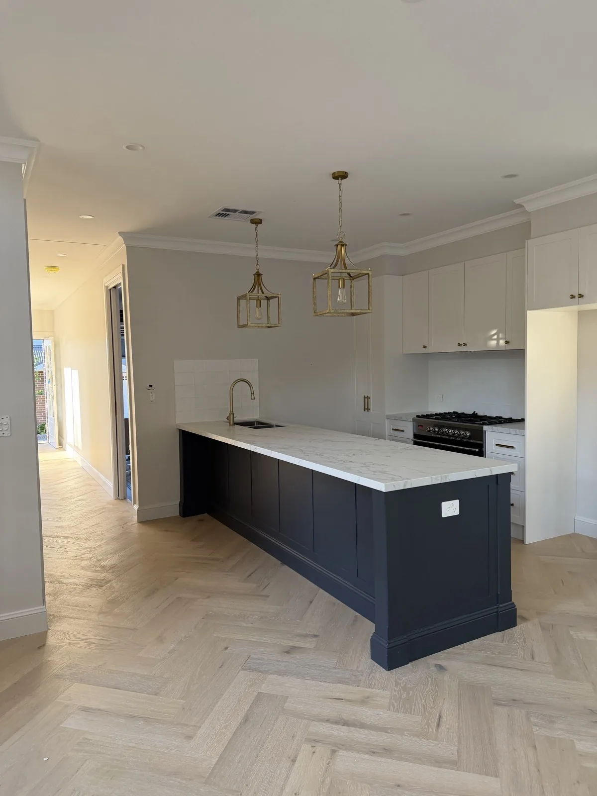 Kitchen with a navy island, white walls and ceiling, and herringbone flooring