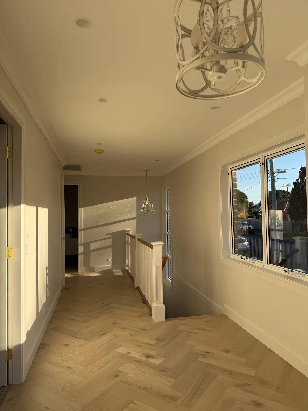 Hallway with white walls, decorative cornice, pendant lights and timber flooring