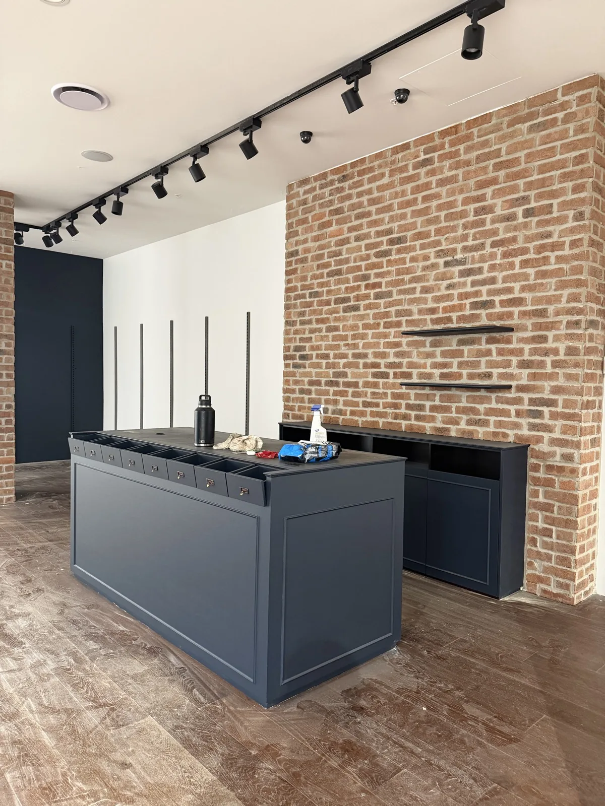 Commercial fit-out with deep navy walls, feature brick and track lighting